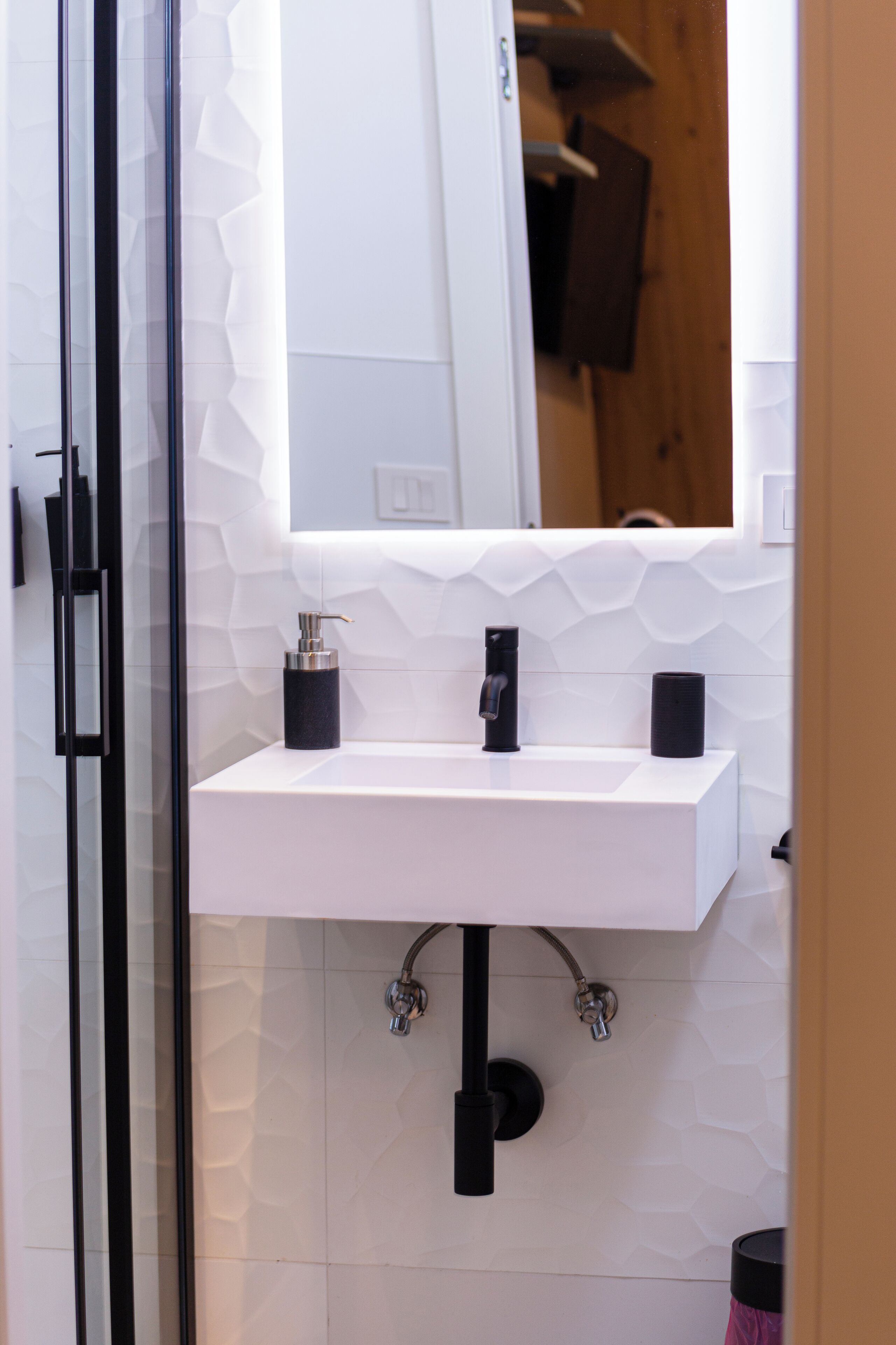 A modern bathroom with a white sink, black faucet, and a glass shower enclosure.