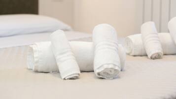 Asciugamani bianchi e ordinati su un letto in una camera d'albergo.