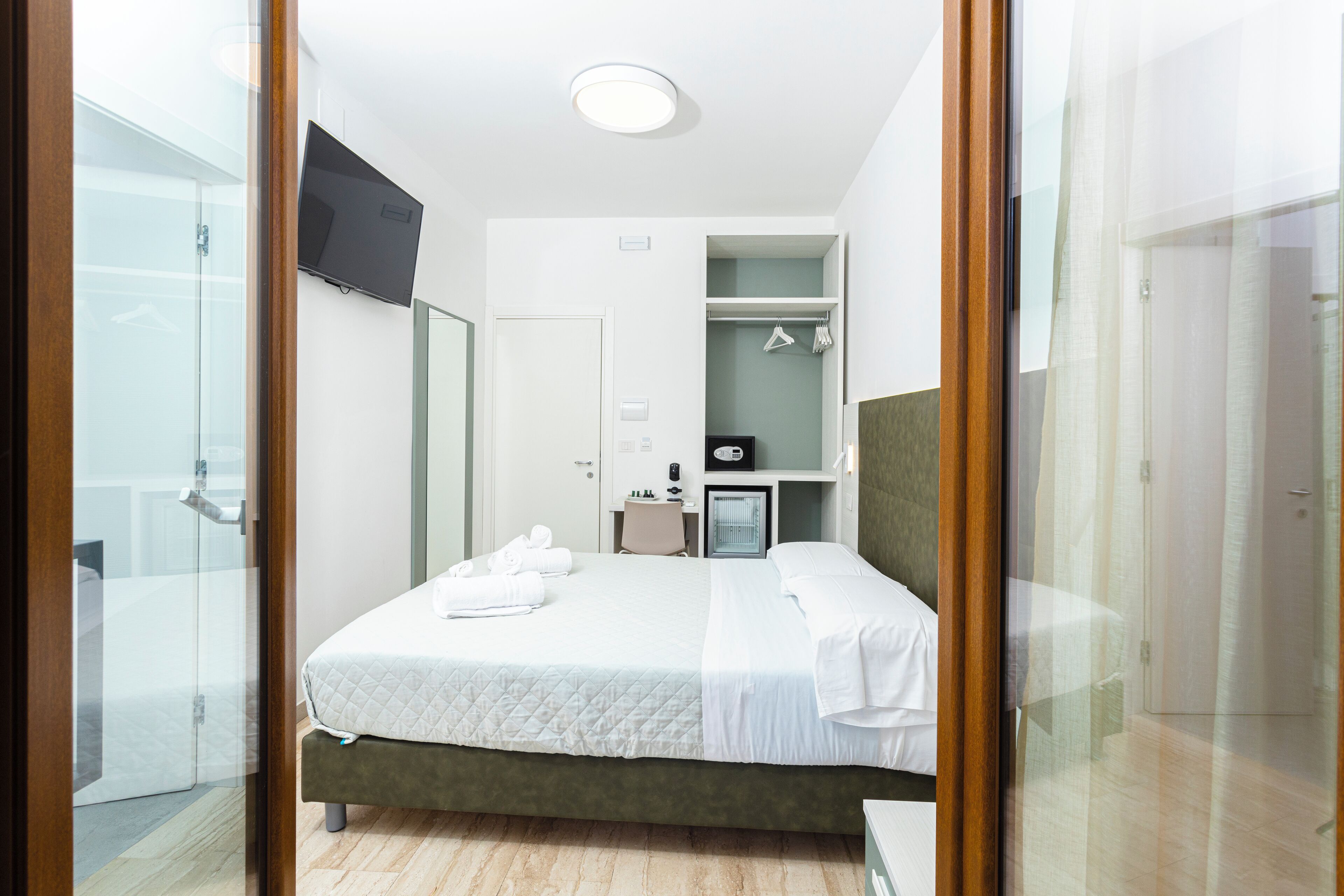 A hotel room with a bed, a desk, a TV, and a walk-in closet.