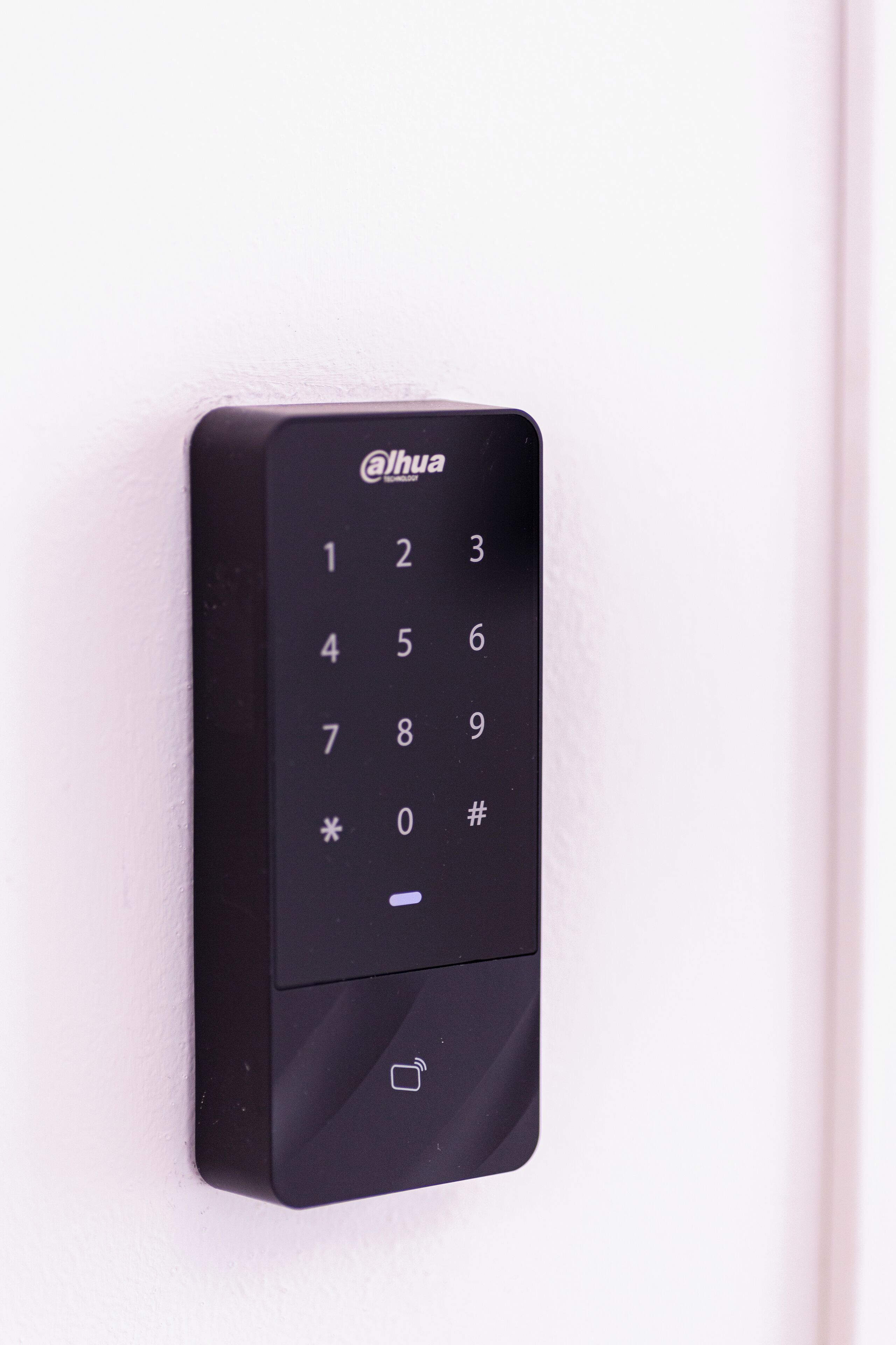 Una serratura elettronica nera @lhua su una porta bianca.