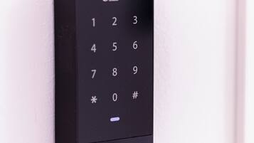 Una serratura elettronica nera @lhua su una porta bianca.