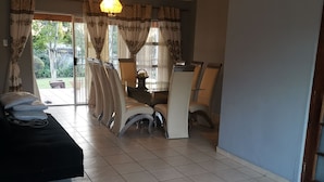 Una habitación amplia con una cama grande, una mesa de comedor con sillas y vistas al exterior a través de un ventanal corredero.