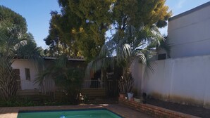 Una piscina rectangular con borde de ladrillo y detalles azules.