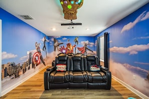 Ein Zimmer mit Schild für Filmabend, einer Deckenleuchte und einem Wandgemälde von Superhelden.