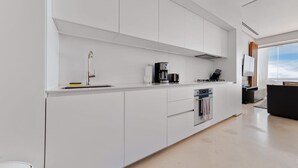 Una cocina moderna con armarios blancos, una cafetera y una estufa.