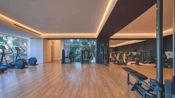 Un gimnasio amplio con máquinas de cardio, equipo de levantamiento de pesas y una banca.