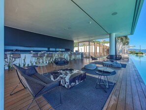 Ein Außenbereich mit Liegebereich, Pool, Holzterrasse und Sitzgelegenheiten.