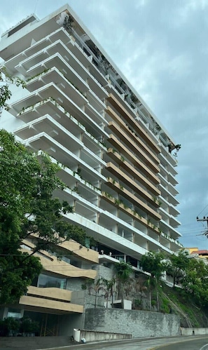 Un edificio de varios pisos con balcones, base de piedra y techo inclinado.