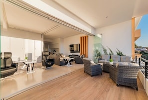 A modern living space with a dining area, kitchen, and balcony with outdoor seating.