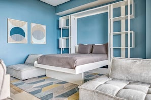 A bedroom with a bed, two sofas, a white wardrobe, and abstract wall art. - Luxury ocean-view condo at SOHO (Puerto Vallarta)