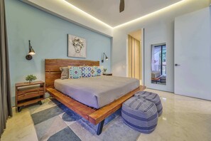 A modern bedroom with a wooden bed, patterned pillows, a nightstand, and a bedside table.