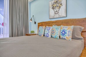 A bedroom with a wooden headboard, a bed with a beige quilt, and colorful patterned pillows. - Luxury ocean-view condo at SOHO (Puerto Vallarta)