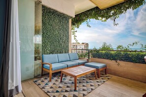 A balcony with a blue sofa, wooden coffee table, and a patterned rug. - Luxury ocean-view condo at SOHO (Puerto Vallarta)