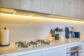 A modern kitchen with a gas stove, a coffee maker, and a knife block. - Luxury ocean-view condo at SOHO (Puerto Vallarta)