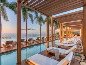 A poolside area with lounge chairs and a view of the ocean. - NEW Luxury Modern Condo in SOHO PV! Best Rooftop! (Puerto Vallarta)