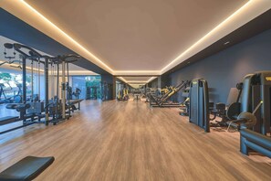 Un gimnasio con equipo de ejercicio, suelo de madera y vistas al exterior.