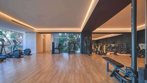 A spacious gym with cardio machines, weightlifting equipment, and a bench.