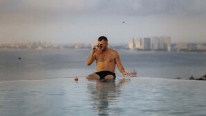 Un homme dans une piscine, avec une vue sur la ville en arrière-plan.
