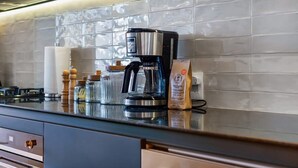 A modern kitchen with a coffee maker, a bag of coffee, and a glass jar on the counter.