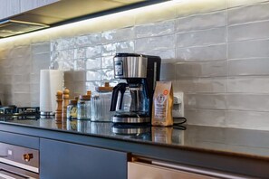 Una cocina moderna con una cafetera, un paquete de café y un tarro de vidrio sobre la encimera.