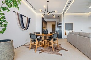 Moderni ruokailutila, jossa on pyöreä puinen pöytä, neljä tuolia ja koristeellinen kattokruunu.