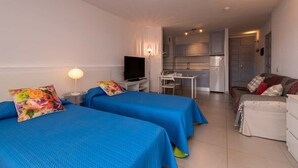 A hotel room with two beds, a TV, a desk, and a kitchenette. - San Marino 28 - Studio (Los Cristianos)