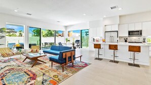 A modern kitchen with white cabinets, a stainless steel refrigerator, and a microwave.