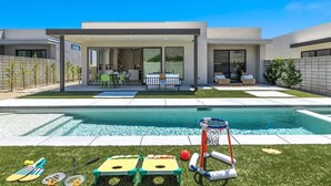 A modern house with a swimming pool, outdoor seating, and a basketball hoop.