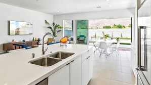 A modern kitchen with a large island, stainless steel appliances, and a view to an outdoor patio area.