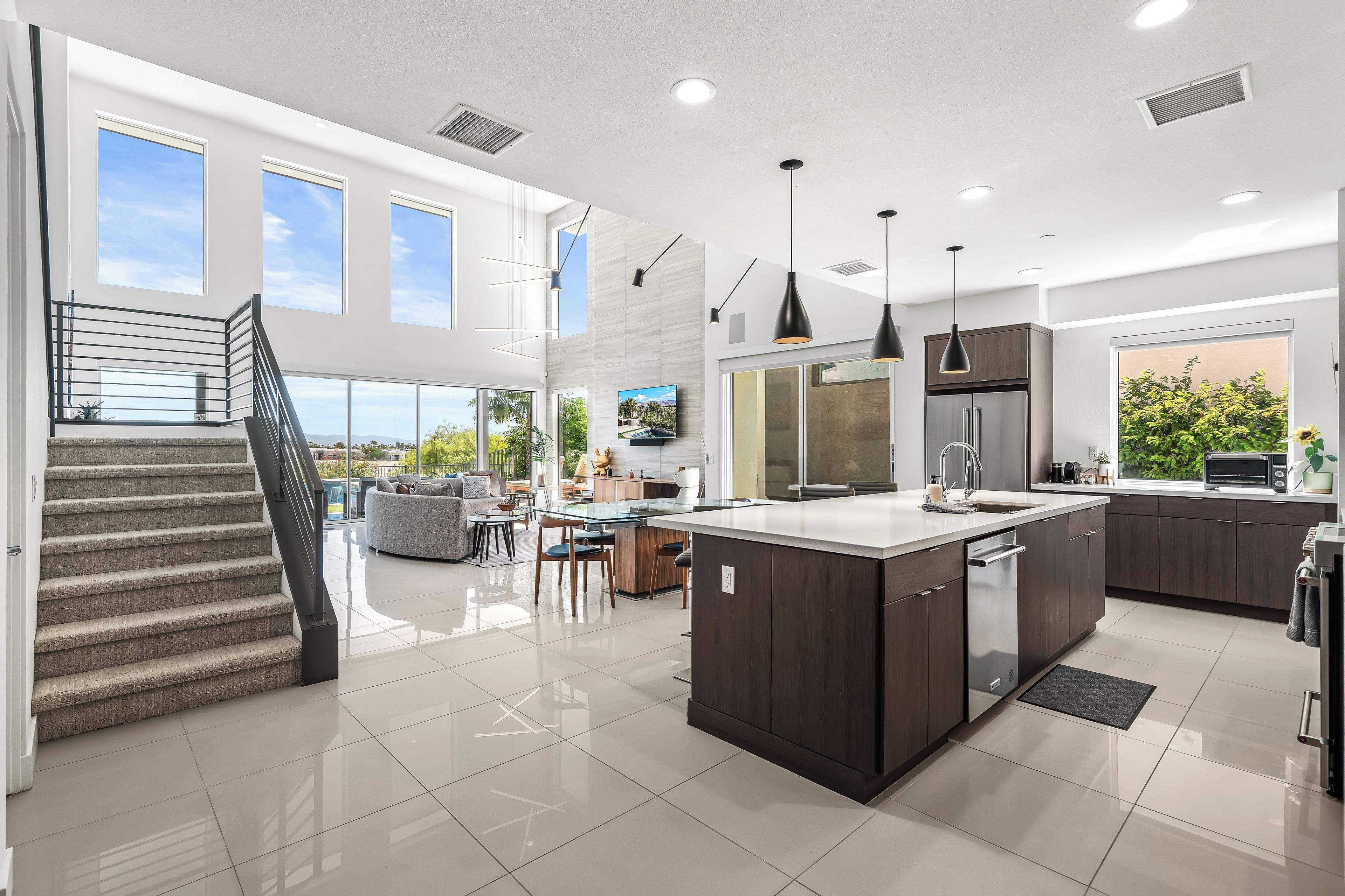 A modern kitchen with a central island, dark cabinetry, and a dining area with a view.