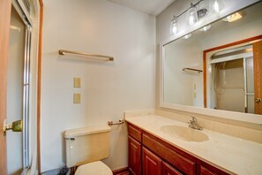 A bathroom with a toilet, sink, vanity, mirror, towel rack, and shower. - Charming 2-bedroom home in Topsail Beach, perfect for family getaways! (Topsail Beach)