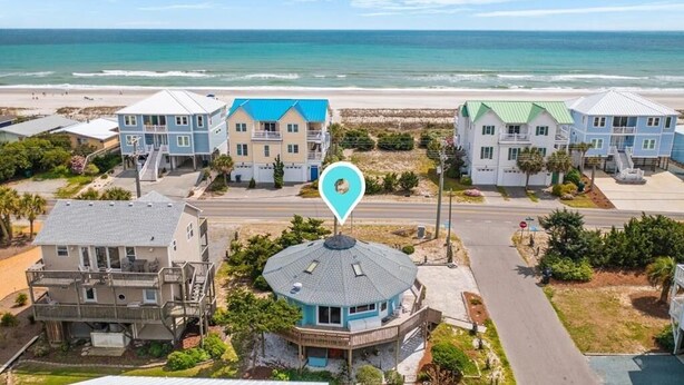Une propriété située en bord de mer, comprenant plusieurs bâtiments, dont un bâtiment principal doté d’un toit en forme de dôme et un bâtiment plus petit avec un toit bleu.