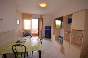 Ein kompakter Wohnraum mit Essbereich, Küchenzeile und kleinem Balkon.