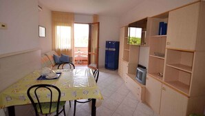 A compact living space with a dining area, a kitchenette, and a small seating area with a view. - Holiday apartment with air conditioning and balcony (Bibione)