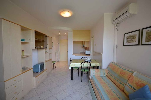 A compact living space with a dining area, kitchenette, and a sofa.