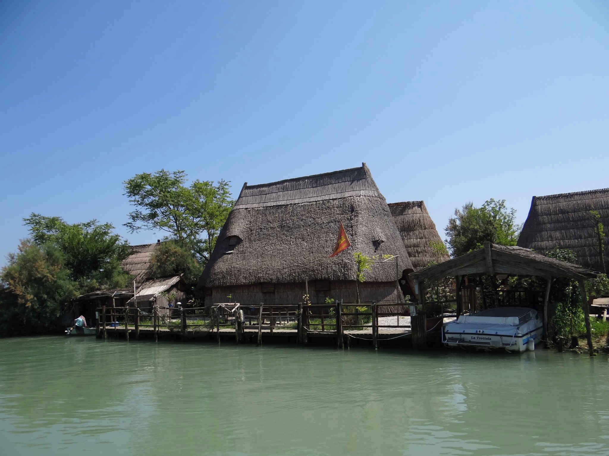 Una casa tradicional con techo de paja junto a un río tranquilo.