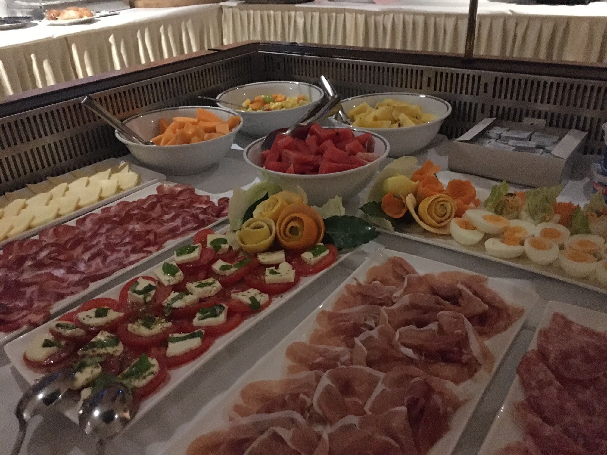 Un buffet proposant une variété de plats, notamment des viandes, des fromages et des fruits.