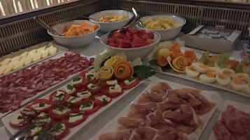 Un buffet proposant une variété de plats, notamment des viandes, des fromages et des fruits.