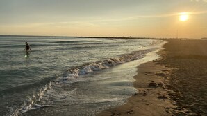 Una spiaggia con onde calme e una persona in acqua.