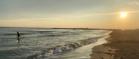 Uma praia com ondas suaves e uma pessoa na água.