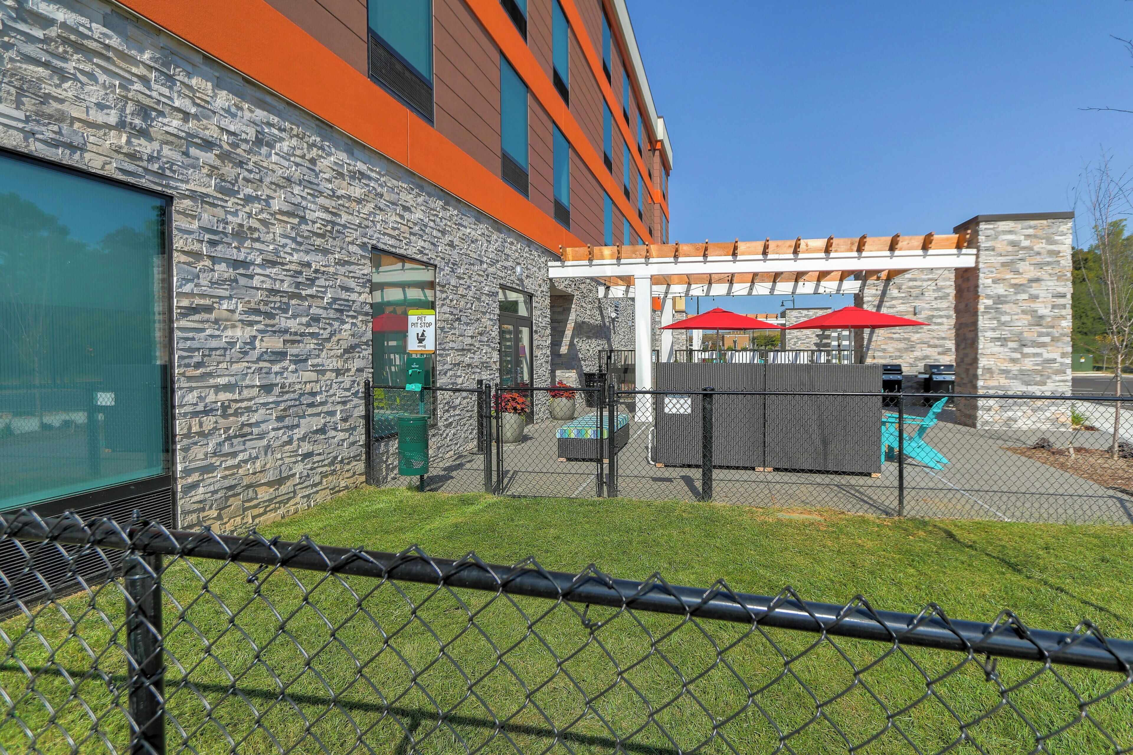 A building with stone facade, outdoor seating, and a fenced patio area.