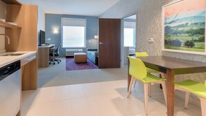 Eine moderne Küche mit Geschirrspüler, eine Essecke mit Tisch und Stühlen, ein Sofa und ein großes Fenster.