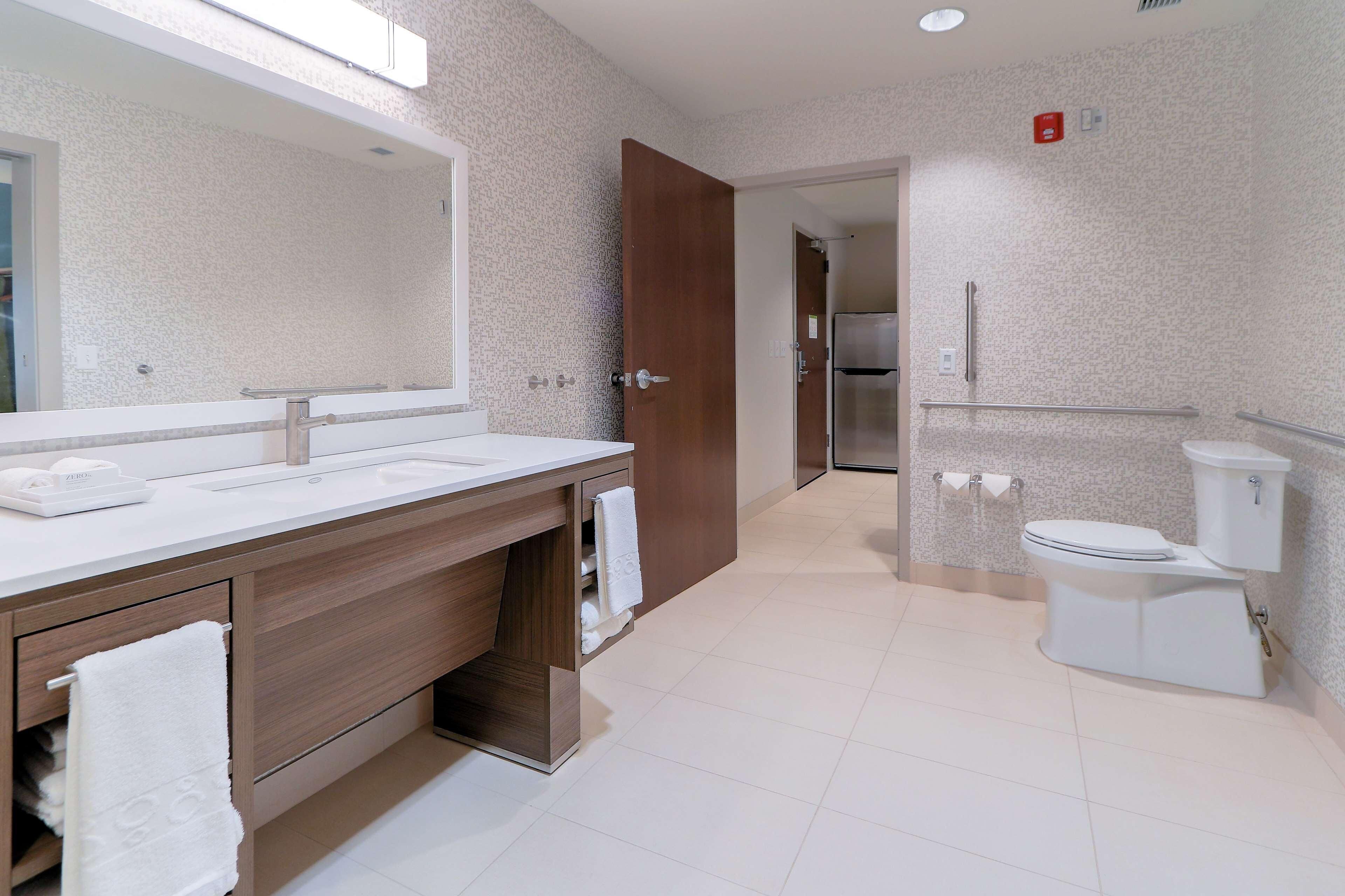 A modern bathroom with a large mirror, two sinks, and a toilet.