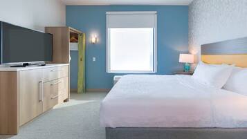 Una habitación de hotel con cama, televisor, armario y ventana con persianas.