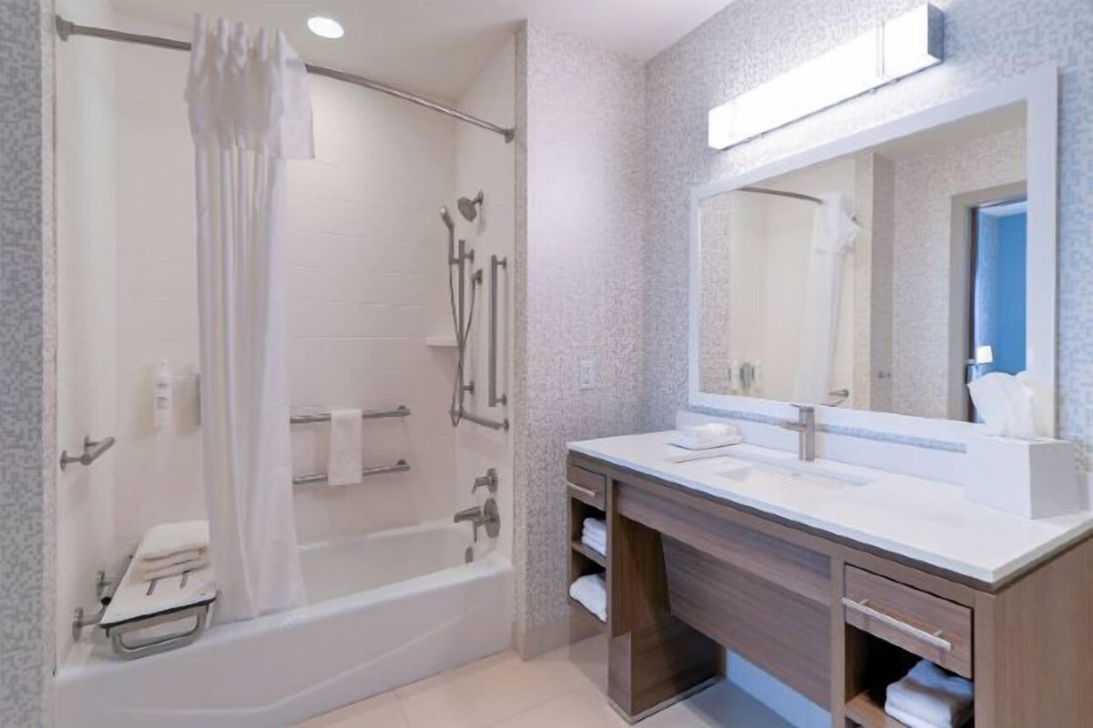 A modern bathroom with a glass-enclosed shower, a large mirror, and a vanity with a countertop.