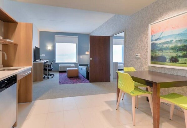 Eine moderne Küche mit Geschirrspüler, ein Essbereich mit Tisch und Stühlen sowie ein Wohnbereich mit Sofa und Fenster.