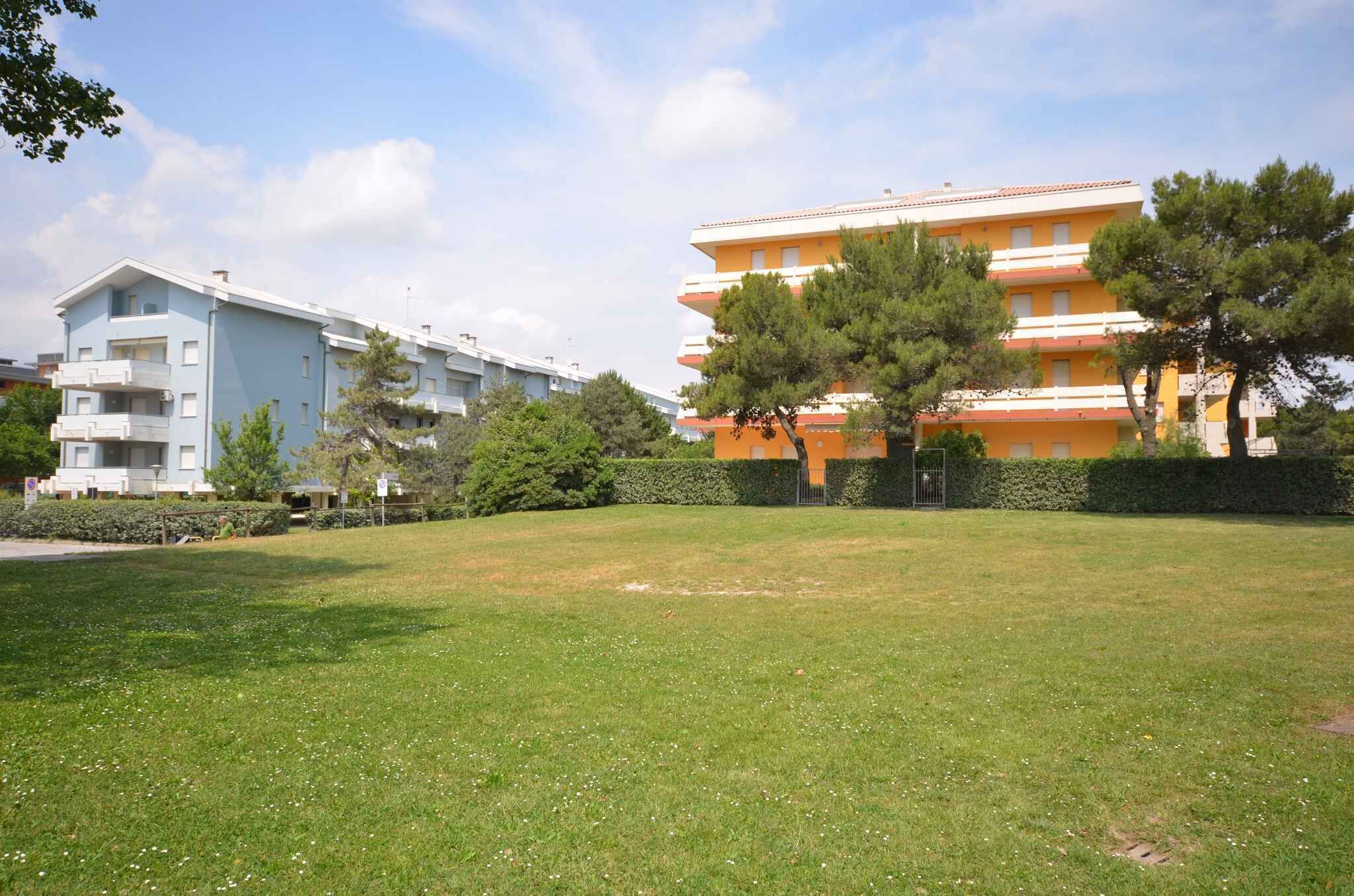 Un immeuble résidentiel doté de nombreux balcons, d’une pelouse bien entretenue et d’arbres adultes.