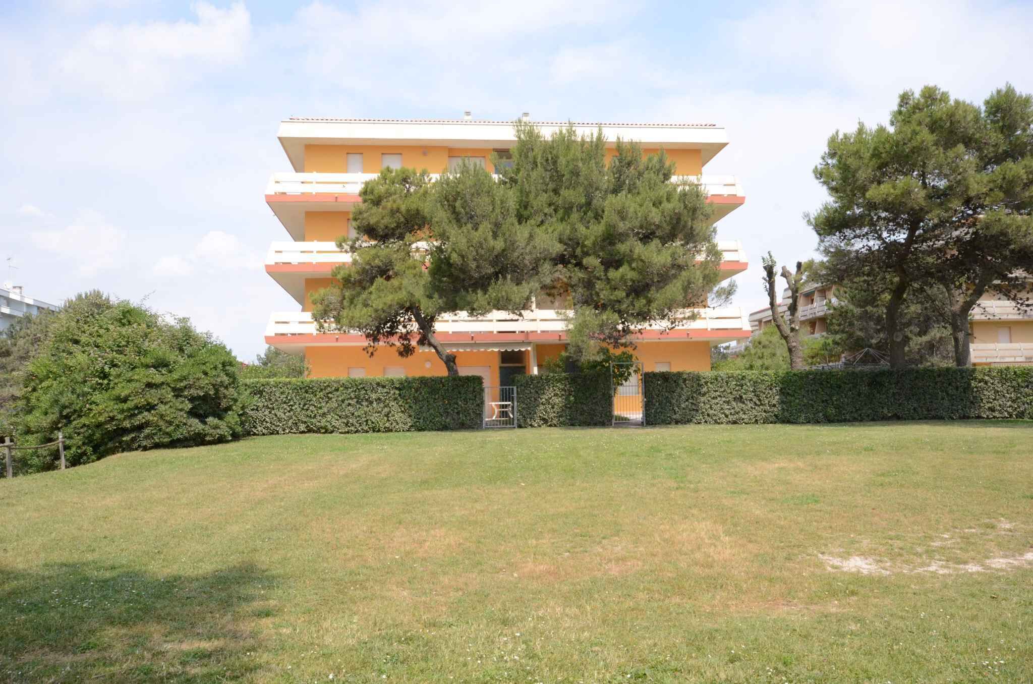 A multi-story building with balconies, surrounded by a well-maintained lawn and hedges.