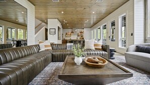 Ein großzügiges Wohnzimmer mit einem großen Ledersofa, einem Holztisch und Blick auf die Küche im Hintergrund.