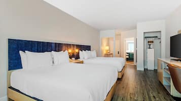 A hotel room with two beds, a TV, a desk, and a walk-in closet.